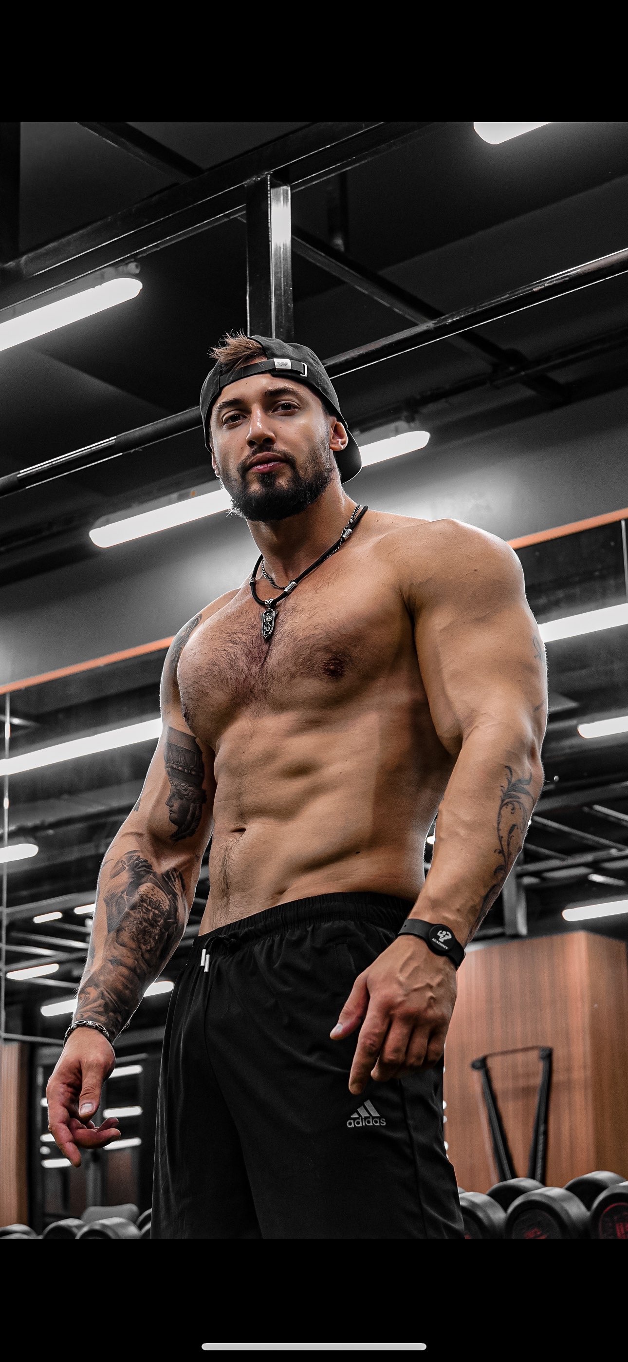 Vlad standing in the gym with a backward cap and black trousers
